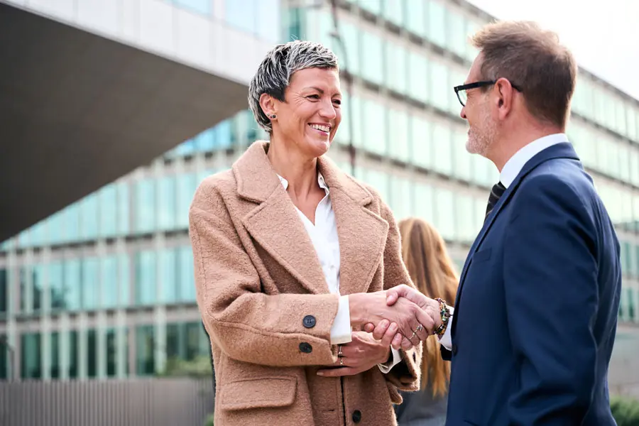 a mature business man shaking hands with a mature business woman