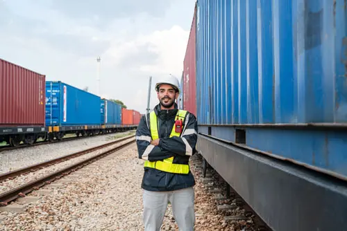 a rail yard worker with shipping containers around him.