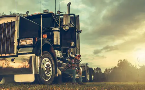 a male worker taking a break by his semi-truck